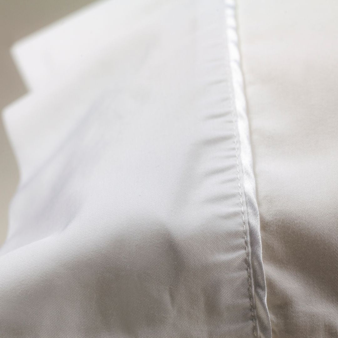 
                  
                    Nollapelli single white pillowcase close up on white satin trim
                  
                