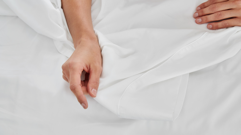 Woman's hands holding Nollapelli's patent-pending cooling bedding fabric made for menopausal women.